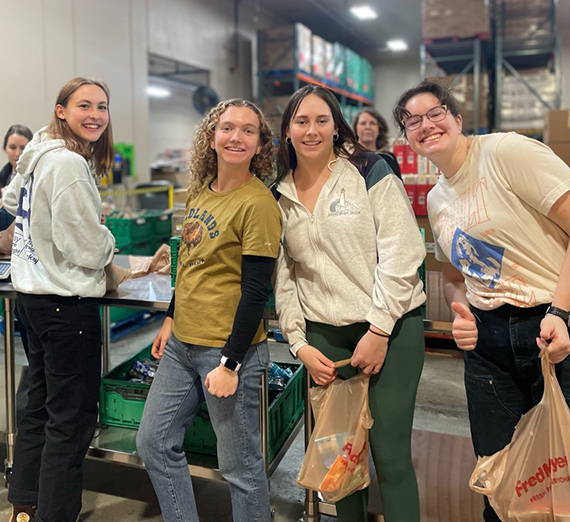 Women's rowing team members packing bags at Second Harvest warehouse 