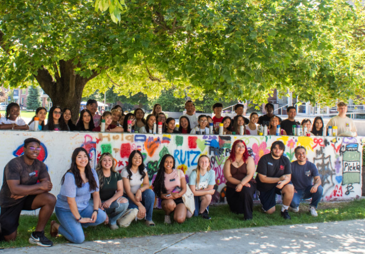 Students Pose in front of spray-painted wall