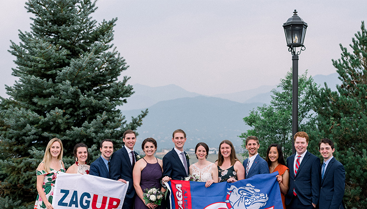 large group of friends and couple with gonzaga flags in front of mountain