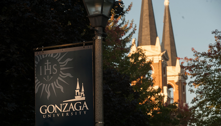 The morning sun lights up a Gonzaga sign and the steeples behind.