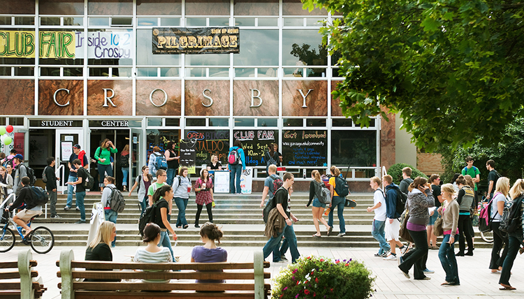 Students busily walk in front of the Crosby Center building.