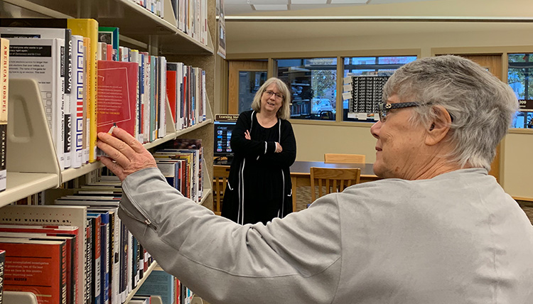 woman pulls book from shelf at library