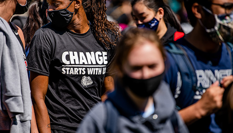 Person of color wearing a shirt that reads change starts with us.