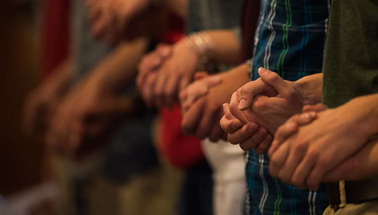 Gonzaga students holding hands in prayer at Mass of the Holy Spirit.