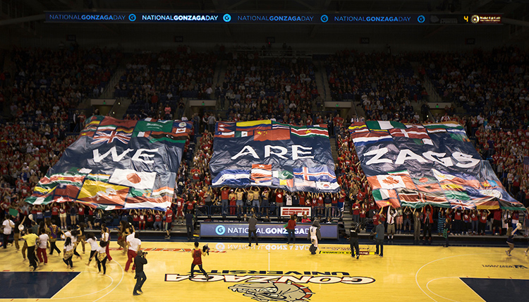 A banner that reads We Are Gonzaga is held by students at halftime during a basketball game.