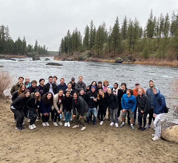 Group of students on the shore of a river.