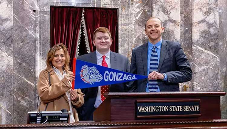 President Passerini pose with a Gonzaga flag along with Zag student and state senator