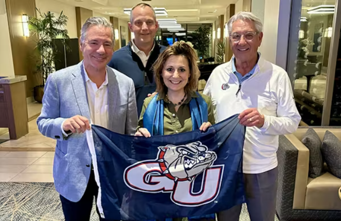 Group of GU President, Athletic Director and Trustees pose with GU flag