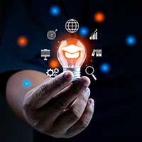 Hand holding a lightbulb with illustrations of ideas surrounding the bulb.