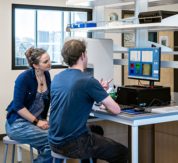 College students refer to a screen displaying test results in an engineering lab