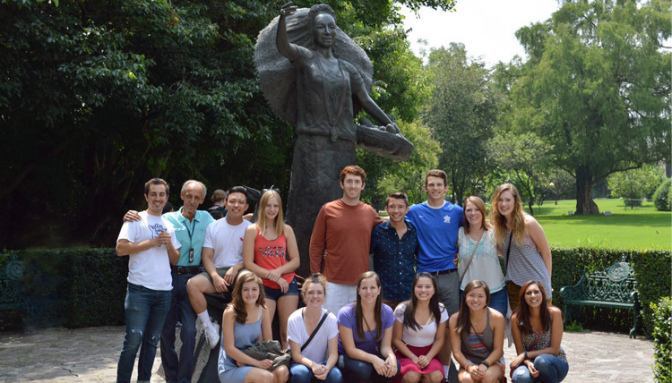 Study Abroad student group posing with a statue