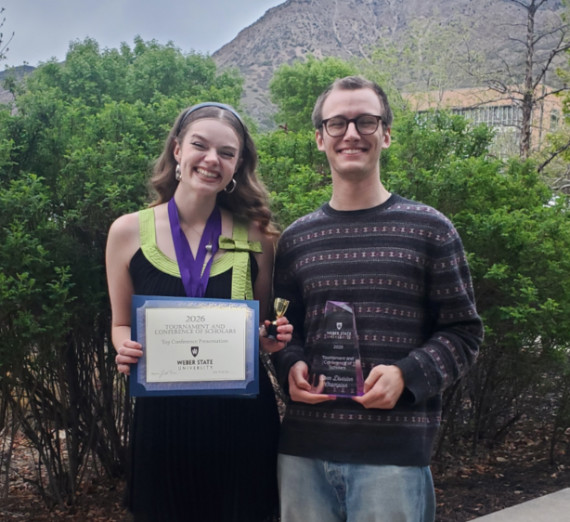 Gonzaga University Debate winners Everett Roe and Kaelyn Wellman posing with certificate and trophy from their 2026 tournament win. 