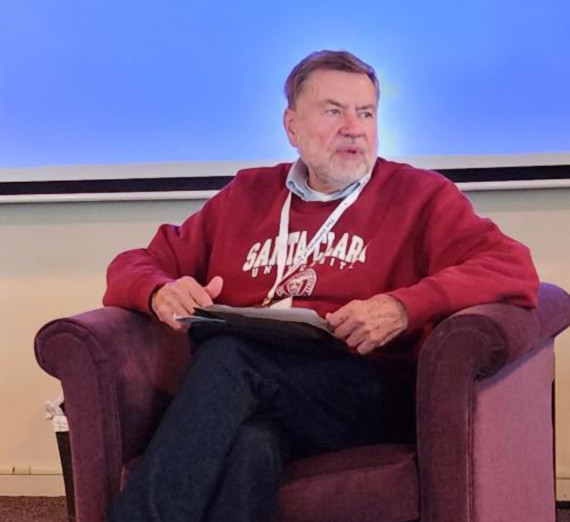 AJCU Communications Conference founder seated and speaking to a group.