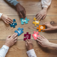 Hands with puzzle pieces on a table. 