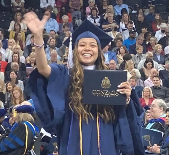 Student at graduation holding diploma and waving