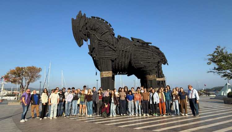 Group of 91 students and faculty visiting the ancient city of Troy in Turkey, standing in front of the iconic Trojan Horse replica during a history department study abroad trip.