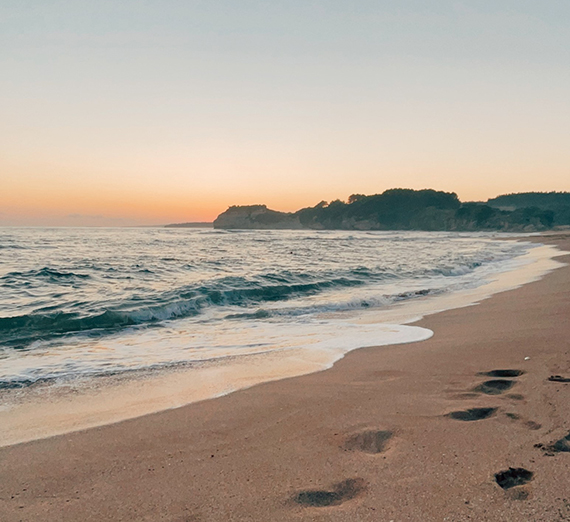 Image of a beach at sunset with footsteps in the sand