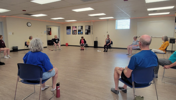 A group seated in a circle in the dance studio ready for group instruction.