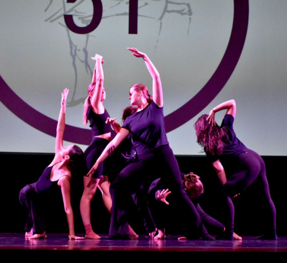 Students dancing in a group on stage.