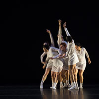 Creative dancers dressed in white on a black background.