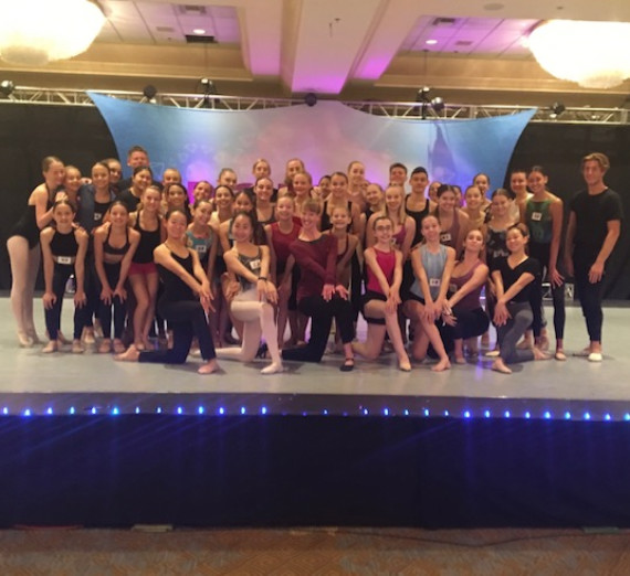 A group of dancers posed on stage for a group photo.