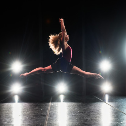 Dancer leaping across an illuminated stage.