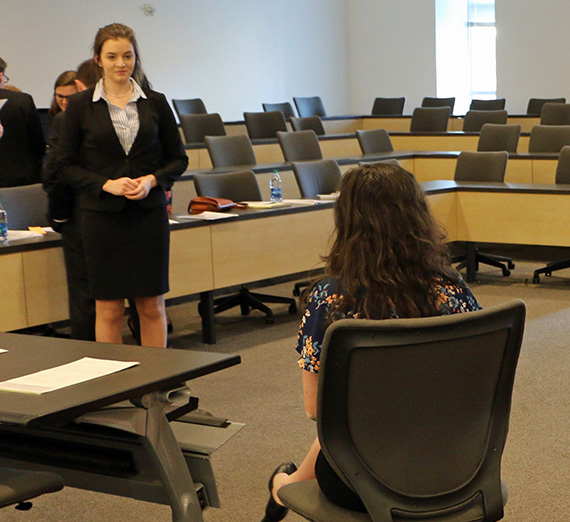Hillary Longoria stands in front of a mock trial court room.