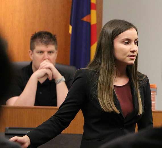Sarah Kohan stands in front of a mock trial court room.