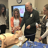 Medical student interns practice with a medical device.