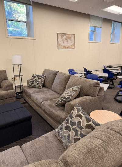 Comfortable lounge area in the Gonzaga Modern Languages Tutoring Center featuring modern gray sofas, geometric-patterned pillows, and collaborative study spaces with blue chairs and tables.