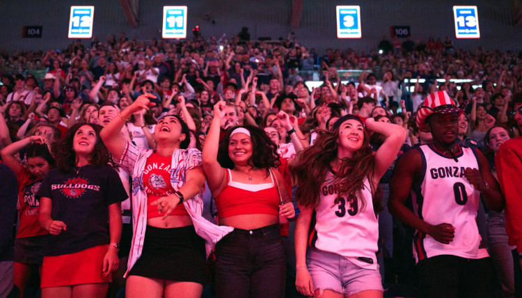 Excited Gonzaga Bulldogs fans packed inside McCarthey Athletic Center during Kraziness in the Kennel event, wearing team jerseys and red-and-blue apparel while cheering for Gonzaga basketball. 