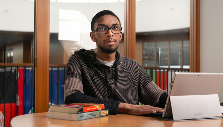 Malik Brown at a table with a computer and books.