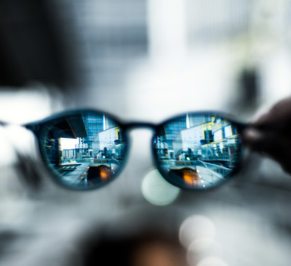 A pair of glasses with blurry scenery around them but clear scenery visible through the lenses.