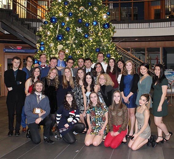 Large group of students posed for a photo in front of a decorated Christmas tree.
