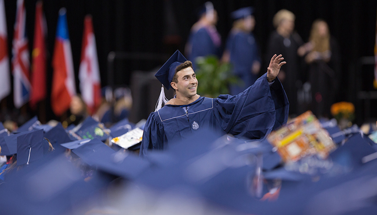 Student at the 2017 Undergraduate Commencement waving to the crowd