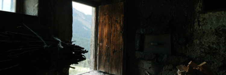 Inside a cabin viewing outside through an open door. 
