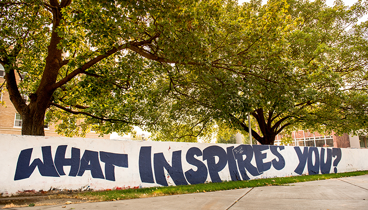 Concrete wall with words painted on. It reads, what inspires you?