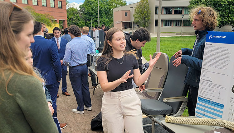 student points out information on a academic poster to an Expo visitor