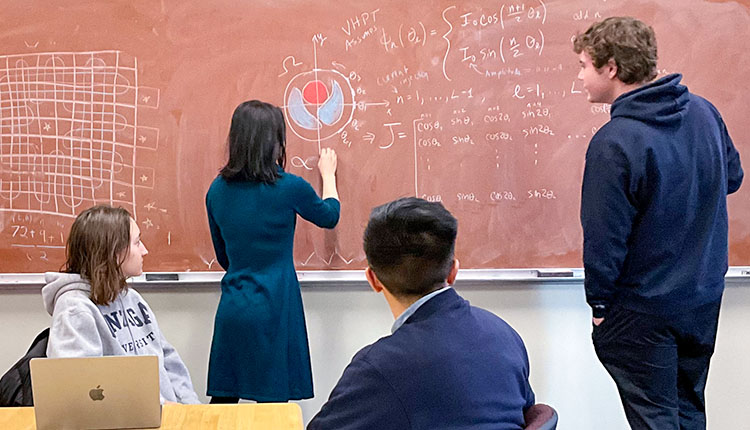 Alsaker at chalkboard with team