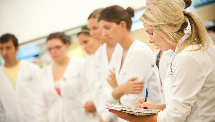 Undergraduate nursing student taking notes in the Sim Lab.