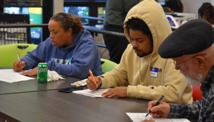 Three community members at the Carl Maxey Center fill out a survey on heat and smoke impacts