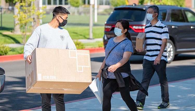 a student and parents carry items to dorm