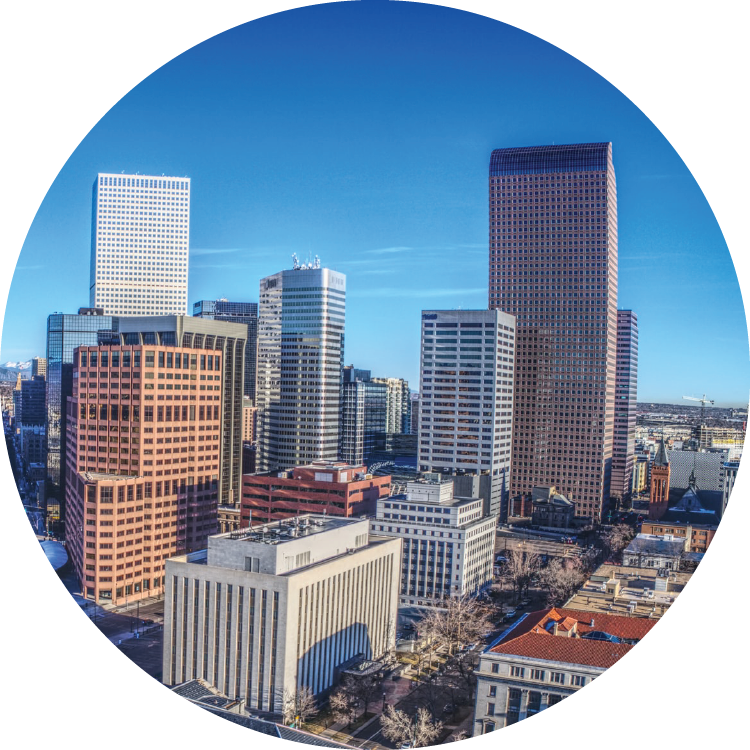 The downtown Denver skyline reaches up into a bright blue, cloudless sky.