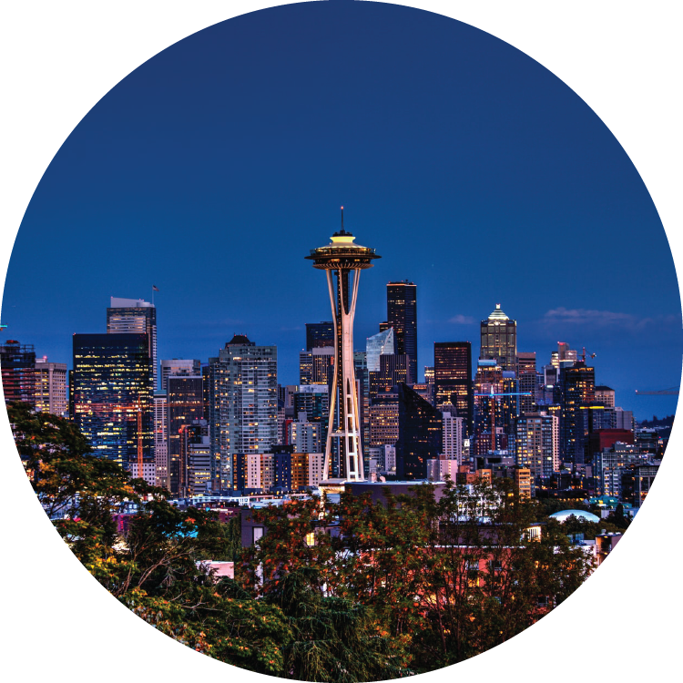 Against a deep blue, twilight sky, the Space Needle and city skyline sparkles with light.