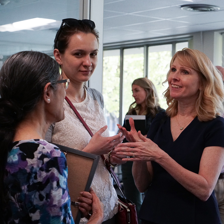 Three faculty members stand in the Crosby lobby having a discussion.