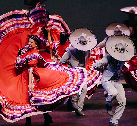Dancers in bright red dresses and wide hats. 