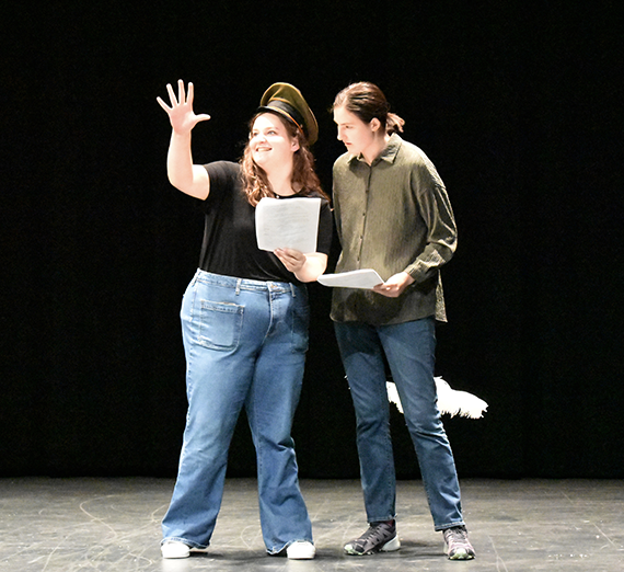 Two actors on stage reading a scene.