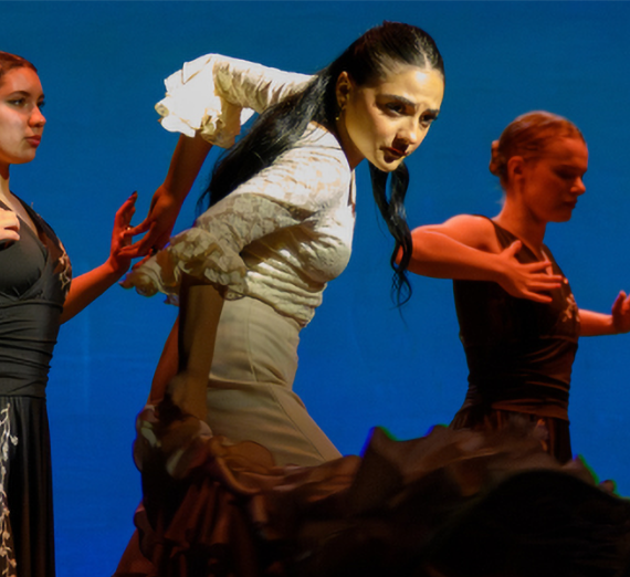 Performers dancing against a blue background.