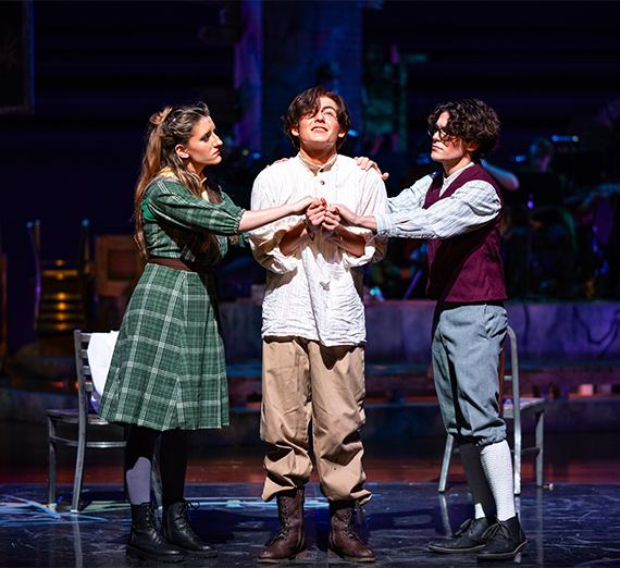 Three actors performing a scene on stage. 