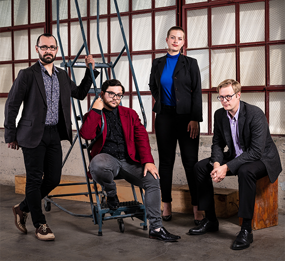 Four musicians each in front of a different colored stripe on the wall and floor holding their instruments.